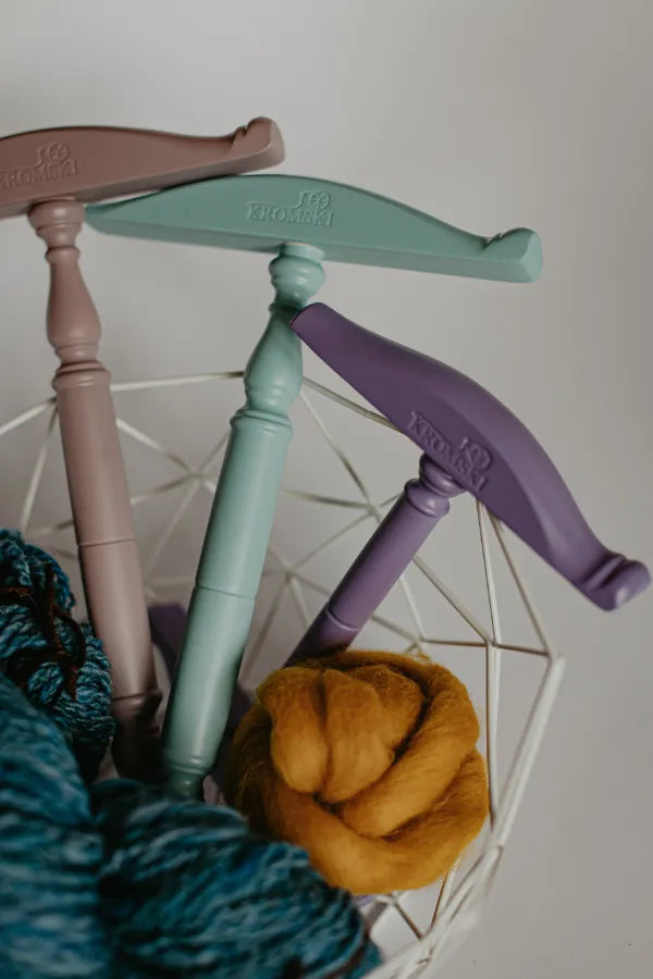 Kromski Kreuzhaspeln in verschiedenen Farben in einem Garnkorb mit Spinnwolle und Handgesponnenem