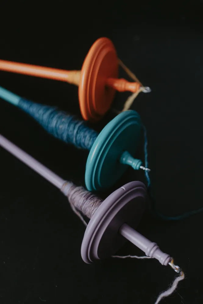 Bunte Kromski Handspindeln mit gesponnenem Garn auf dunklem Hintergrund