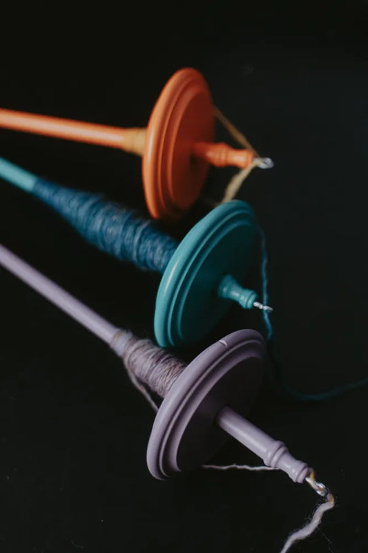 Bunte Kromski Handspindeln mit gesponnenem Garn auf dunklem Hintergrund