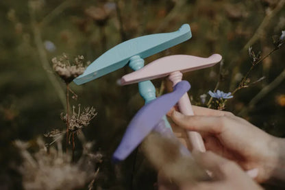 Kromski Kreuzhaspeln in verschiedenen Farben - gehalten in der Hand, umgeben von Wiesenblumen